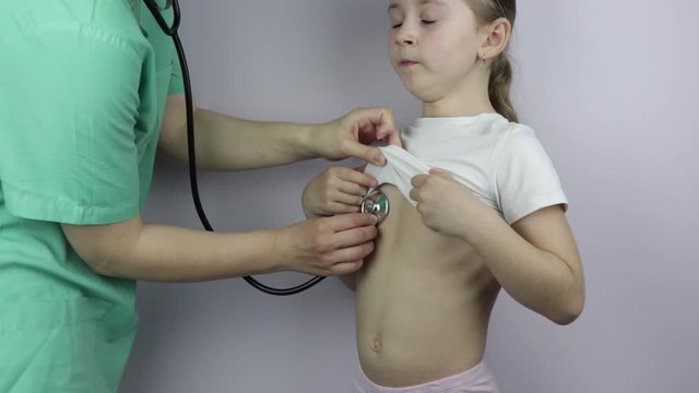 Family modern woman doctor in the office listens to the lungs of a child with a phonendoscope, a girl of Caucasian appearance of seven years. check for coronavirus, covid-19