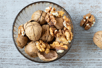 whole and cracked walnuts in bowl on wooden table horizontal