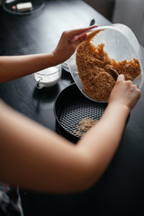 girl puts crushed products in a baking dish on a black table