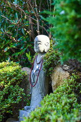 Buddhist statue peeking out of a bush. Haedong Yonggung Temple, in Gijang-gun, Busan, South Korea