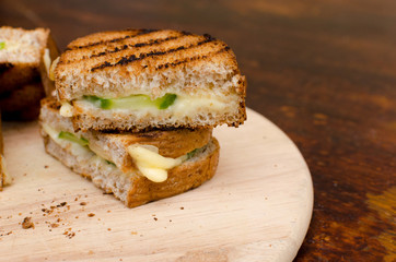 grilled sandwich with cheese and cucumber on a wooden tray