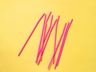 Scattered pink straws on yellow background. Pink straws randomly placed on the yellow background.