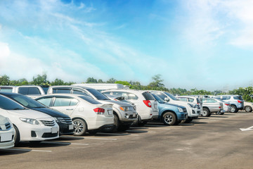 Obraz na płótnie Canvas Car parked in large asphalt parking lot with trees, white cloud, blue sky background.