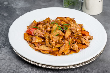 Fried potatoes with pork in a white plate on a gray background
