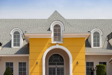 Roof shingles on top of the house against blue sky with cloud, dark asphalt tiles on the roof background.