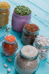 Various grains in glass cans. Blue wooden background.