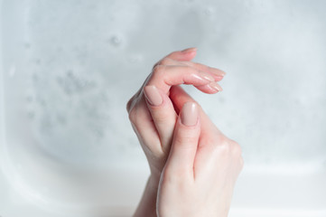 woman washes her hands over water with foam