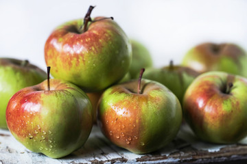 red and green apples in water drops on a wooden table close up on a light background