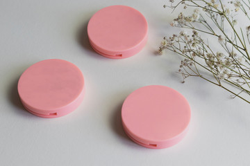 empty eyeshadow containers, brand label mockup, cosmetic containers on white background with a branch of white flowers, natural brand concept