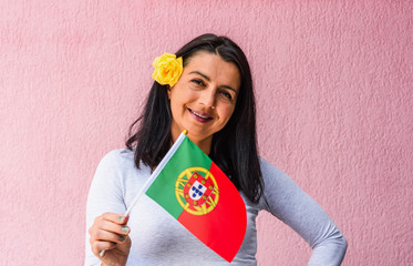 Woman holds flag of Portugal in front of isolated wall background