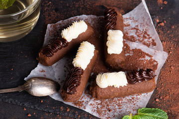 Chocolate rum balls with green mint tea on dark background. Brown sweets with cream