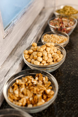 ciotoline in vetro con varie prodotti di frutta secca quali, noccioline , arachidi,  ecc, salta una superficie in marmo
