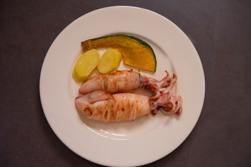Grilled squid stuffed with vegetables.Seafood.Baked squid on white plate.Cooking BBQ/Selected focus