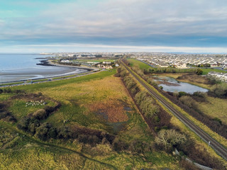 Aerial view on rail road to Galway city, Ireland,  empty Ballyloughane beach, Cloudy sky. Rails act as leading line to town.