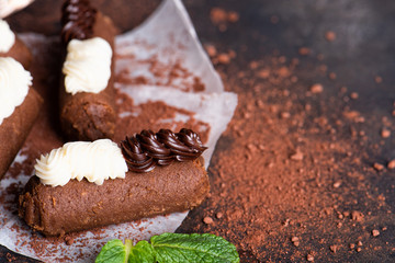 Chocolate rum balls with green mint tea on dark background. Brown sweets with cream