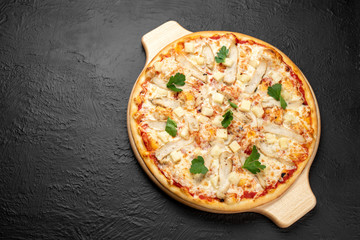 Pizza on a black background on a tomato base with mozzarella, grilled chicken, pineapples and parsley, there is a place for the inscription