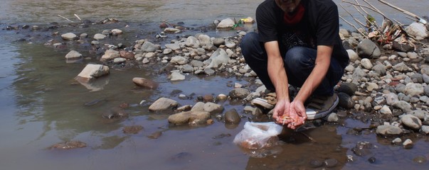 Panoramic view on the river bank. a man was squatting on the riverbank holding fish seeds.