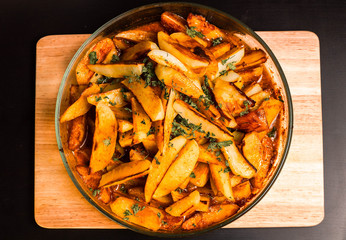 Golden fried potato in a glass plate. Rustic potato with a crust, spices and herbs.
