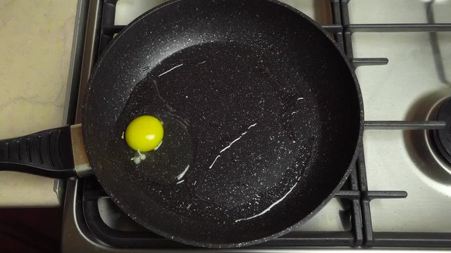 Fried eggs in a pan. A female hand breaks an egg and fries in a pan.