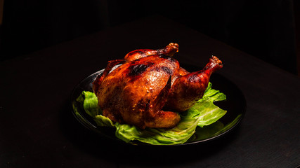 Fried Chicken with a crispy crust on a black plate, with a substrate of lettuce leaves. Just a shiny sour sweet chicken. Home cooking.
