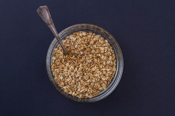 Organic wheat grains with spoon in a plate. Dark blue background.