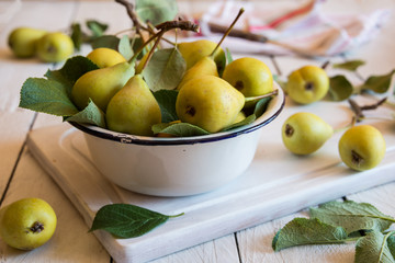 Fresh organic pears with leaves on white wooden background