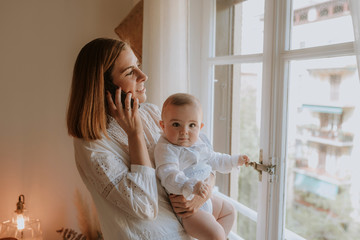 Young mother talks on the phone with baby in her arms