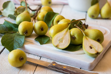 Fresh organic pears with leaves on white wooden background