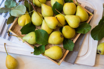 Fresh organic pears with leaves on white wooden background