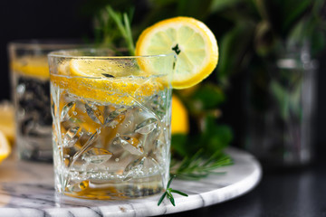 Lemonade, lemon mojito cocktail, cold, iced,refreshing summer drink in glasses with slices of lemon on marble tray. Side view. Copy space