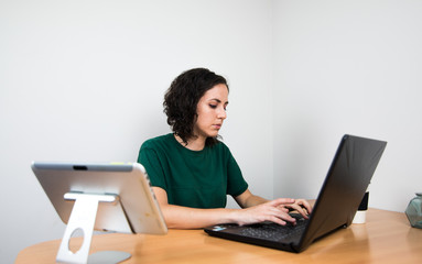 young girl working from home, with the computer and the tablet. home office