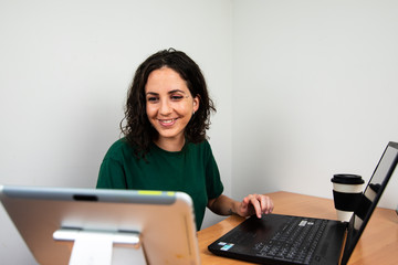 young girl working from home, smiling at her tablet.