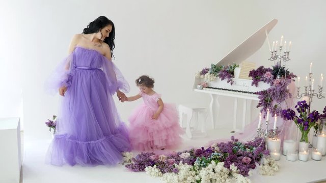 Mother and daughter walking together among lilacs in the studio
