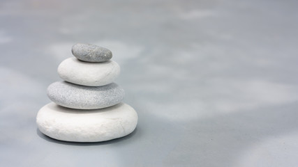 Fototapeta na wymiar Four grey roundstones on clear gray background. Spa stones, zen like concept. Pastel colors