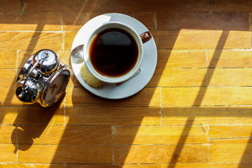 Alarm clocks and coffee mugs are placed on a wooden table by the window in the morning to prepare to work at home to help reduce the spread of coronavirus covid-19. The concept of work from home