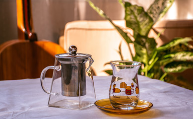 an empty glass teapot and classic turkish tea glass on the table, alive colorful closeup