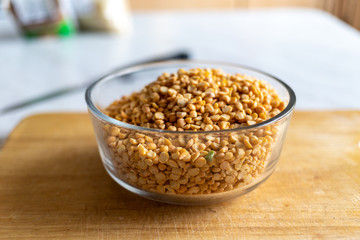yellow dry peas in a transparent deep bowl. it stands on a table and a wooden Board in the kitchen. raw.
