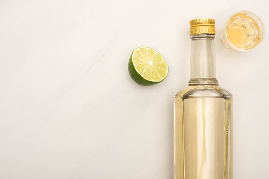 top view of golden tequila with lime on white marble surface
