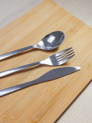 Spoon, fork, and knife on the wooden surface.