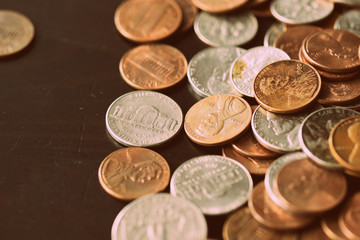 American cents are scattered on an old black wooden surface close-up. Retro style toned