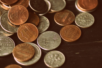 American cents are scattered on an old black wooden surface close-up. Retro style toned