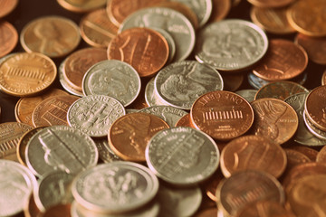 American cents are scattered on an old black wooden surface close-up. Retro style toned