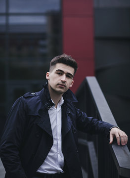 Handsome young man in suit and coat posing in city