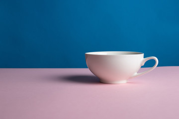 an empty white Cup hangs on a pink and blue background