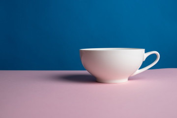 an empty white Cup hangs on a pink and blue background