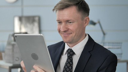 Businessman Using Tablet for Internet at Work