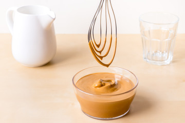 How to make coffee from dalgon. Step by step photo instruction. Step 4. Beat the cream. Ingredients - instant coffee, sugar, water, milk and a whisk for whipping on a wooden background