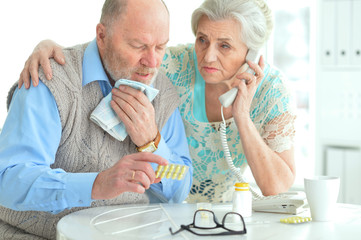 Portrait of sick senior couple calling to doctor