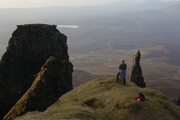 A hiker on a mountain peak above a highland landscape. 