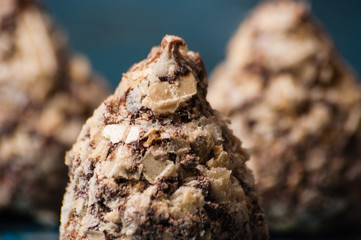 Chocolate candies in waffle crumbs close-up macro on a blue background, side view
